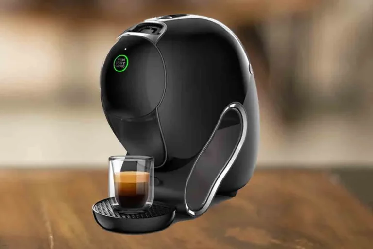 Dolce Gusto Neo Vale a Pena? Apesar de só fazer café preto, é boa em alguns aspectos. 20 Para ilustrar a postagem "Dolce Gusto Neo Vale a pena" a imagem é composta pela cafeteira de cápsulas Dolce Gusto Neo de cor preta com um copo com café dentro. Essa cafeteira está em uma mesa de madeira e o resto do fundo está desfocado.